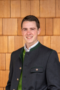 Junger Mann in Tracht vor Holzfassade, regionale Landwirtschaft Lungau, bäuerliche Familienbetriebe