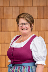 Bäuerin im bunten Dirndl vor Holzfassade, regionale Lebensmittel Lungau, Nachhaltigkeit