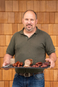 Landwirt präsentiert regionale Lungauer Fleischspezialitäten im Hofladen für nachhaltigen Genuss